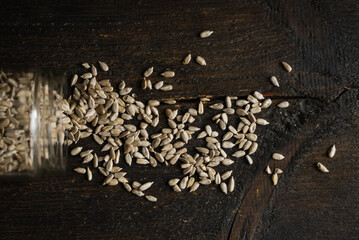 Sunflower seeds scattered on the wooden vintage table from a jar.