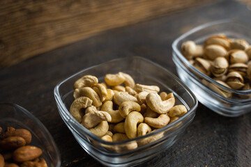 Almond, cachew and walnut in a small plates which standing on a black table. Nuts is a healthy vegetarian protein and nutritious food.