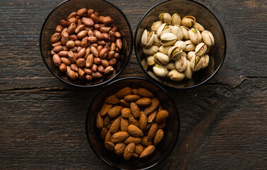 Almond, pistachio and peanut in a small plates which standing on a black table. Nuts is a healthy vegetarian protein and nutritious food.