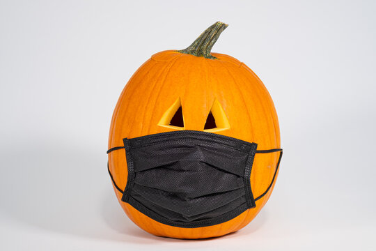 Carved Halloween pumpkin wearing a Covid 19 face mask isolated on a white background
