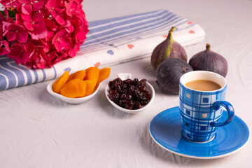 a cup of coffee, dried apricots and cranberries, fresh figs, hydrangea branch