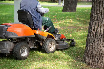 Petrol lawn mower. An employee uses a lawn mower to clean the lawn.