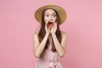 Shocked amazed young brunette woman 20s wearing pink summer dotted dress hat posing screaming with hands gesture near mouth looking camera isolated on pastel pink wall background studio portrait.