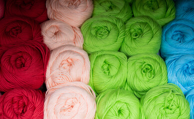 Fototapeta premium Close-up of skeins of thread in red, pink, green and blue pastel colors. Thread background