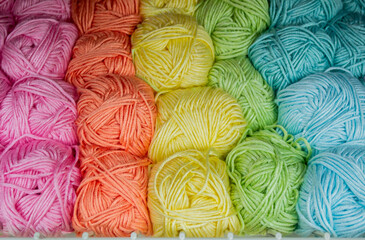 Close-up of skeins of thread in turquoise, blue, yellow, orange and green pastel colors. Thread background