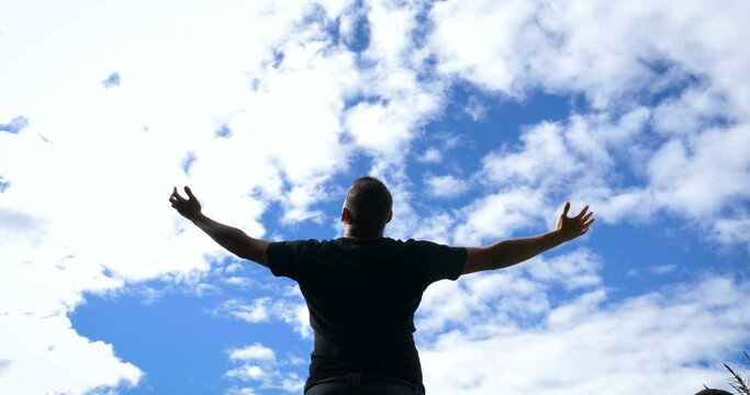 Reach out for the sky - A man opens out his arms facing a vibrant misty sky standing on top of a hill.
