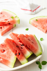 Juicy ripe sweet red watermelon slices with mint in a plate on a white background