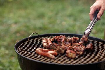 Hand of  man grilling meat kebab and sausages on a grill