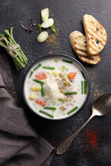 Creamy soup with salmon, asparagus beans, potatoes and croutons in a deep bowl on a black background. Flatlay, vertical. Background image, copy space
