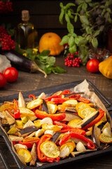 Baked vegetables in the oven, eggplant and zucchini, bell peppers and onions with spices, vegetables on a baking sheet on a wooden background