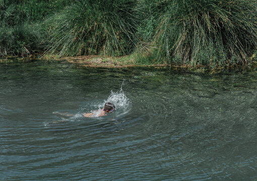 Ni&ntilde;o nadando en un r&iacute;o de agua cristalina