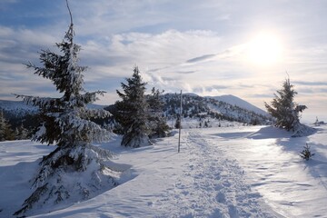 Fototapeta na wymiar Beautiful winter mountain views at sunset during a snowshoe hike along the red ridge trail in the Low Tatras, Slovakia - trampled tracks in the snow around Sedlo pod Skalkou