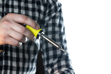 The master in a plaid shirt on a white background holds a soldering iron in his hand.