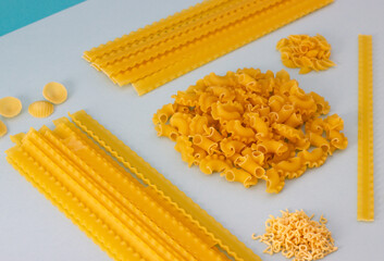 Different types of uncooked pasta, blue background. Healthy and vegan food. Top view.
