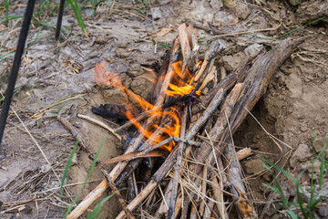 Lighting a fire for cooking in the camp. The firewood is burned in a specially dug pit to avoid fire. Tripod is stand above the pit