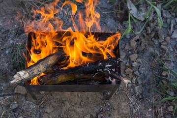 Firewood is burned in the grill to turn into coals. Cooking meat on coals. Dinner at the camp at sunset