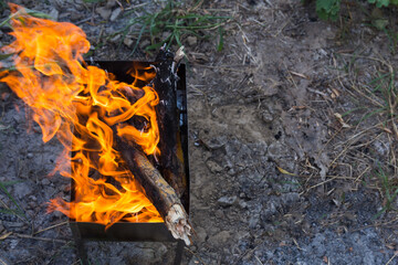 Firewood is burned in the grill to turn into coals. Cooking meat on coals. Dinner at the camp at sunset