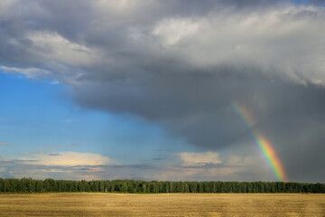 summer landscape with rainbows, cloudy skies, fields and forests.