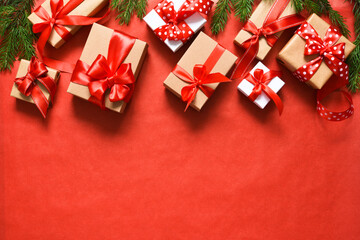 Gift boxes with red ribbons and candy canes. Beautiful Christmas composition on a red background with fir.