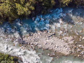 Aerial view of whitewater rapids in river in Swiss alps. Wild water from above in nature.
