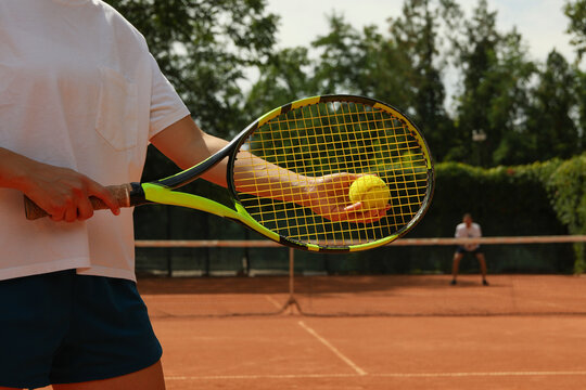Woman hold racket and tennis ball on clay court
