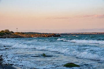 Rocky beach and waves crashing at sunset