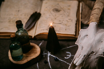 White goat scull with horns, open old book, magic spells, runes, black candles