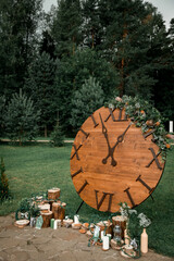 Wedding decor  in rustic style.  Composition  of a wooden dial decorated with flowers, a wooden box, candles and sawed wood.