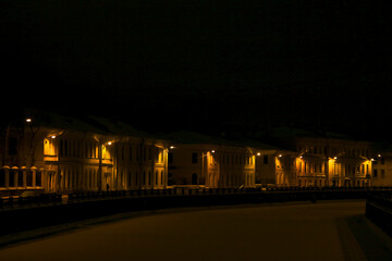 night scene: winter landscape facades of houses on the frozen river embankment illuminated at night