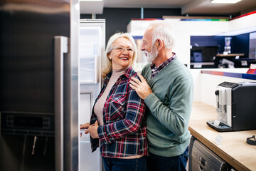Fototapeta na wymiar Senior husband and wife, satisfied customers choosing fridges in appliances store.
