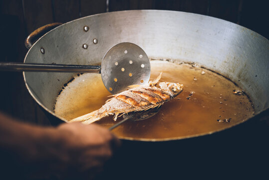 Person cooking fish in pan, close-up, Tulum, Mexico