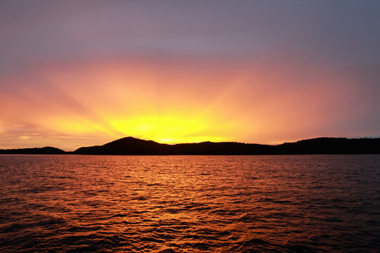 Sun setting over the equator in the Raja Ampat islands of West Papua in the Halmahera sea, Indonesia