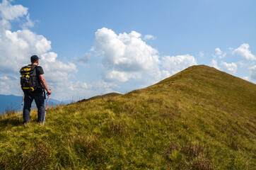 Fototapeta na wymiar Hiker with backpack walking on trail uphill to mountain top in Carpathian mountains, Ukraine
