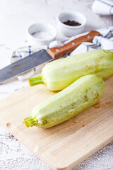 Fresh zucchini on a wooden board with a knife
