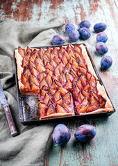 Traditional German Zwetschgenkuchen with sliced plums offered as top view on a rustic backing sheet...