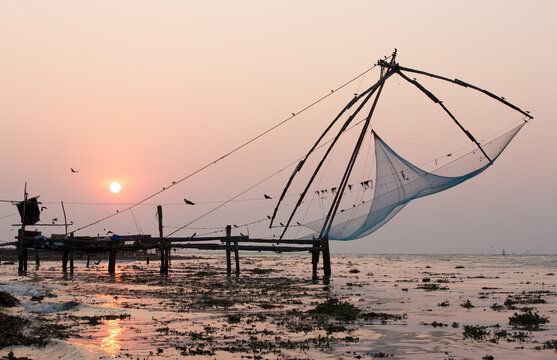 Pier and fishing nets on beach at sunset, Kochi, Kerala, India