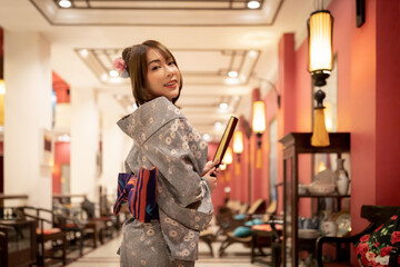 Young woman in traditional Japanese kimono is standing and smiling to camera, Japanese concept of...