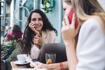 Woman smiling in cafe while friend speaking on phone