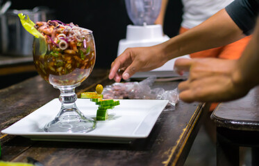 shrimp cocktail served in a glass goblet. chef garnishing shrimp cocktail
