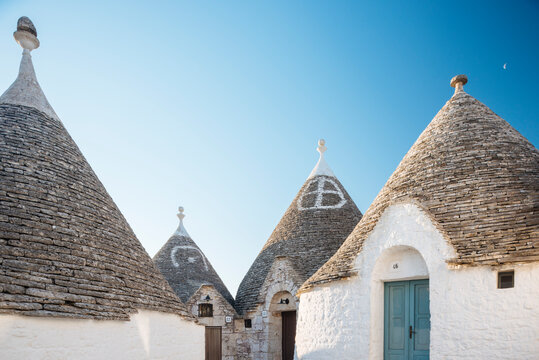 Four whitewashed trullo houses with conical roofs, Alberobello, Puglia, Italy