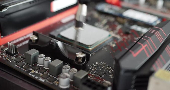 A computer repair technician installing a new gaming pc cpu on a motherboard with a screw driver tool.