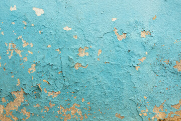 A fragment of an old stone wall covered with plaster. The layer of blue paint swelled and partially peeled off. Background. Texture.