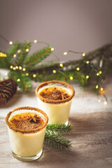 Obraz na płótnie Canvas Eggnog with cinnamon and nutmeg for Christmas and winter holidays. Homemade eggnog in glasses on wooden table surface, shallow depth of the field, copy space.