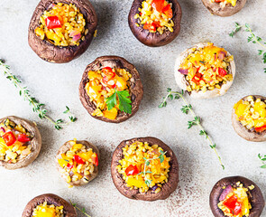 Stuffed portobello mushrooms with bulgur, vegetables and aromatic herbs on a concrete background. Vegetarian food. Selective focus. Top view.