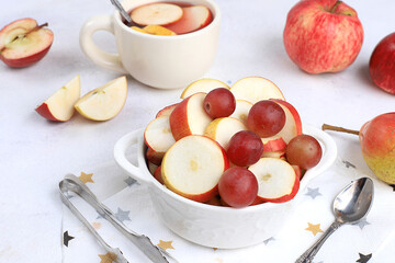 Fruit salad, healthy breakfast with ingredients, yogurt with muesli, apples, pears and grapes on a light table. The concept of healthy and natural food, lifestyle. selective focus