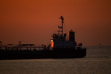 船橋に日の出を受ける沖止まりの船