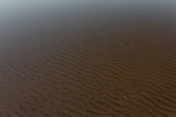 transparent water in lake with brown, patterned ground