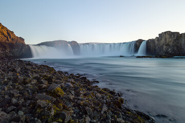 Long exposure shot of Godafoss (Waterfall of the gods) and some rocks in the foreground, Iceland.
