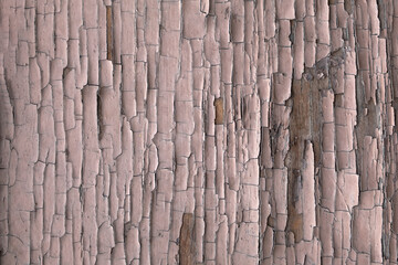 old wooden board with cracked and peeling pink paint. rough surface texture
