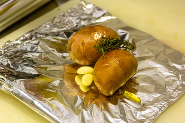 Potatoes with garlic, oil and thyme are prepared for baking in foil